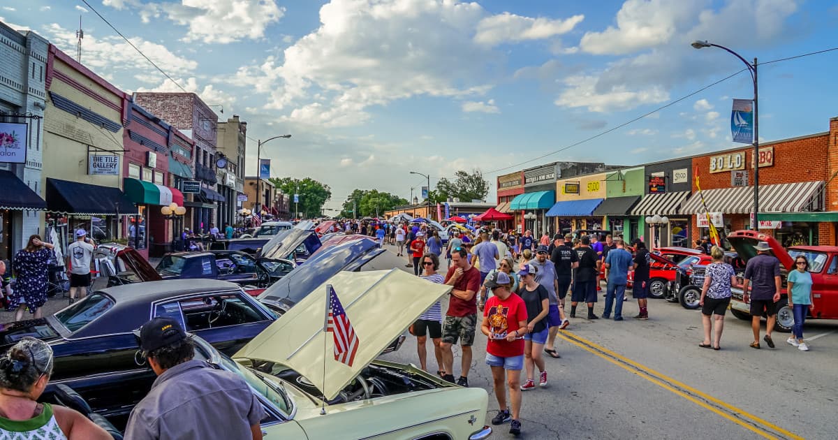 Multitud junto a autos clásicos en un día soleado en el centro histórico de Wylie, Texas, durante una exhibición comunitaria de autos