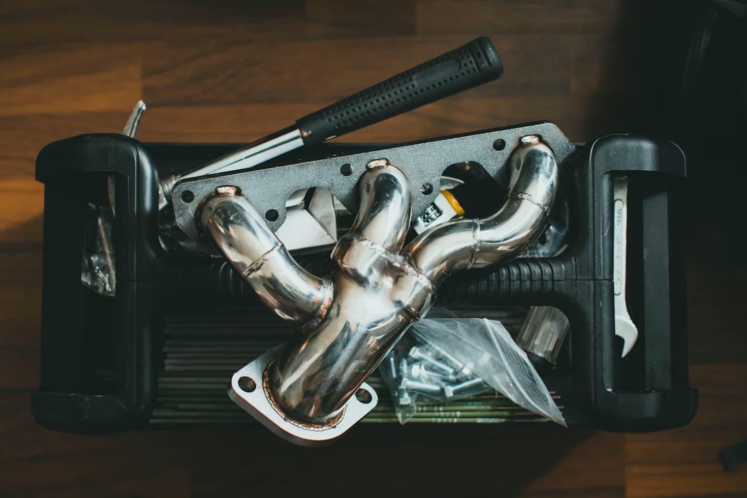 Underside view of a catalytic converter mounted in a vehicle exhaust system, the emissions component vulnerable to theft and failure