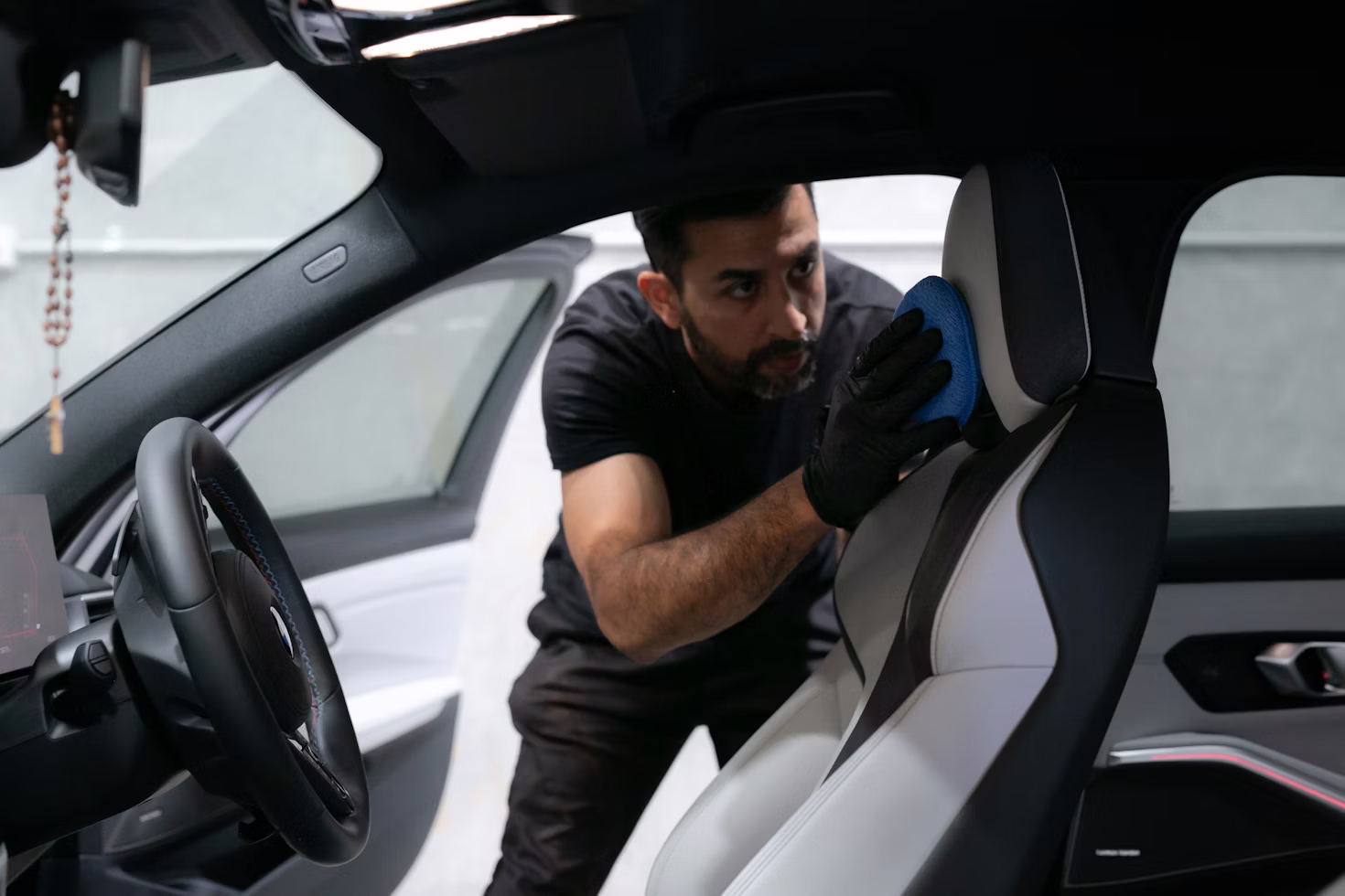 Mechanic inspecting a used vehicle on a shop lift, performing a pre-purchase inspection before a buyer signs the title